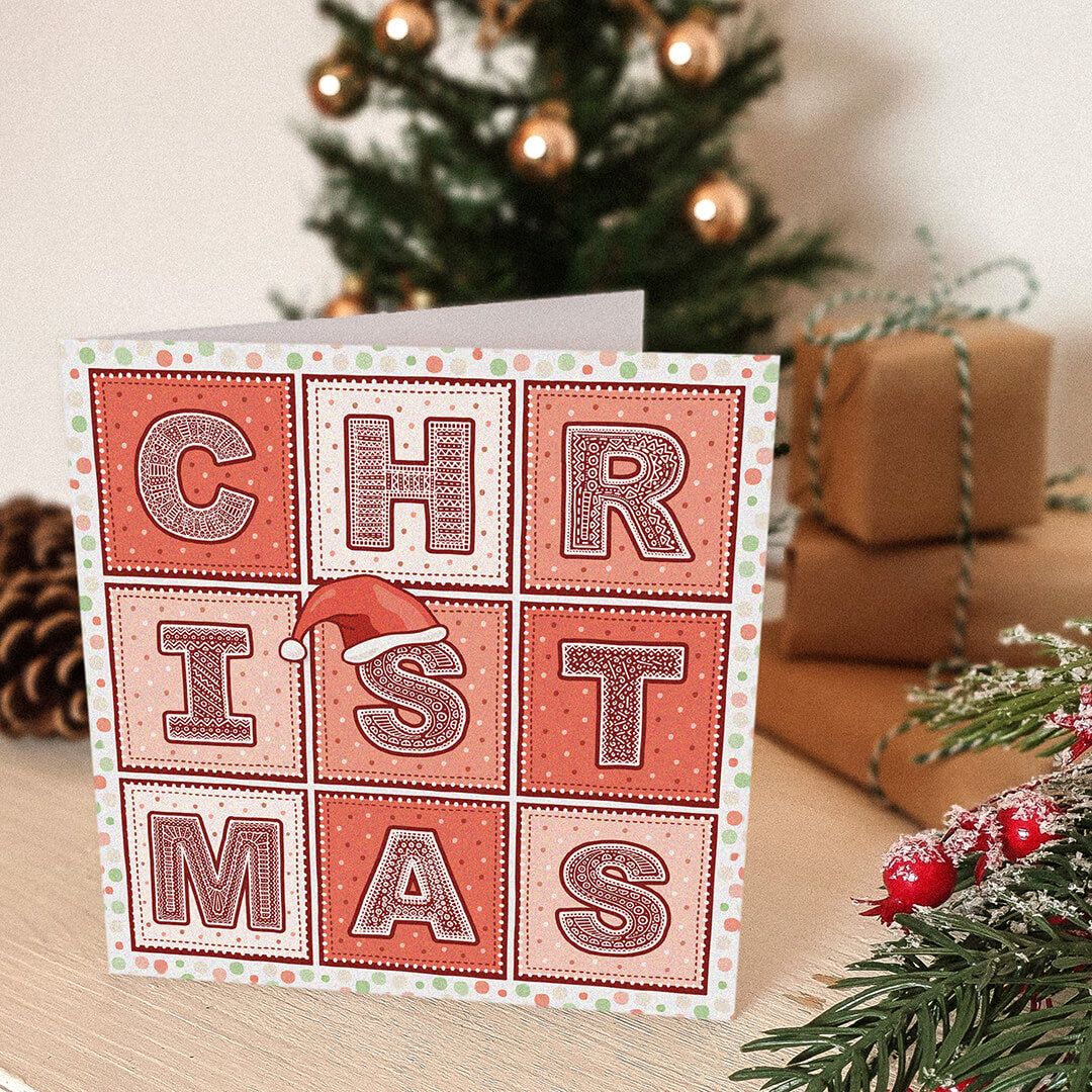 Christmas card with decorative text in front of a Christmas tree and presents.